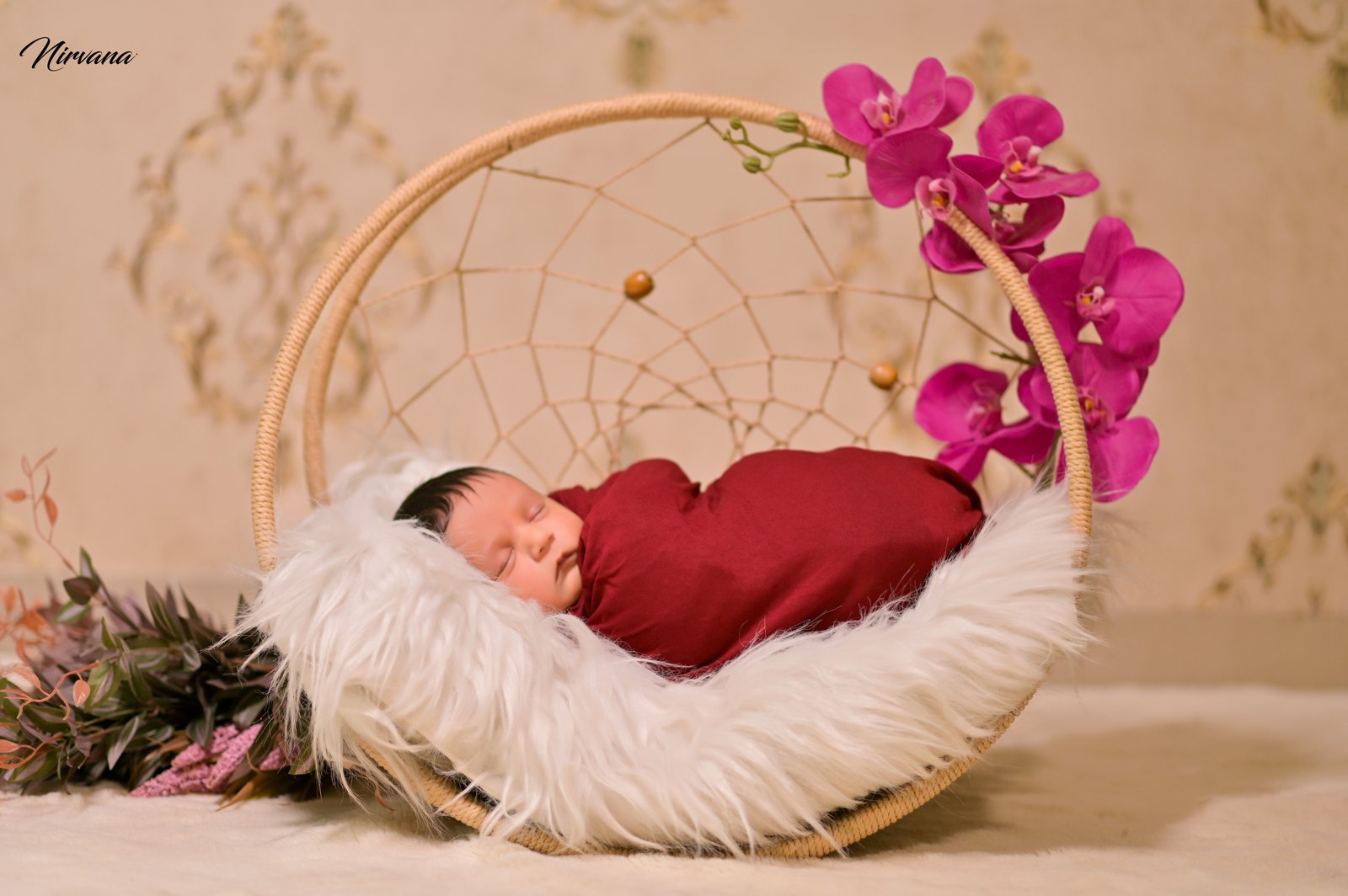 Sleeping newborn safely wrapped in a floral studio setting Sleeping newborn safely wrapped in a floral studio setting